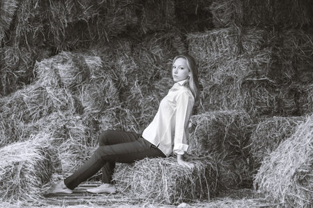 beautiful young girl with a shirt and trousers sitting in the barn. Hay store with stables