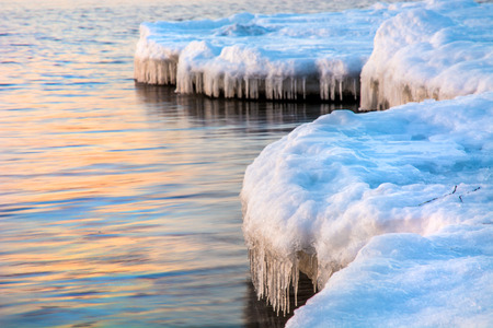 High cliffs into the sea, all in ice. Crag at sunset in the ice. a beautiful landscape from the outgoing Sun. Winterの写真素材