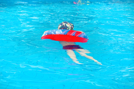 little boy swims, cheerful child jumping in the pool in the circle, open-air swimming pool, splashの写真素材
