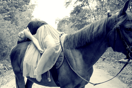 a young, blonde girl posing with a horse, a beautiful girl and a strong horse. in the forestの写真素材