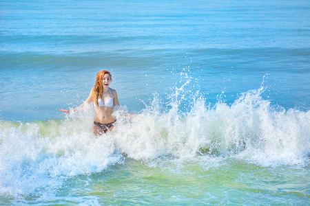 beautiful girl in bikini posing on a deserted beach. white sand, turquoise sea and a young girl. with a sunny dayの写真素材