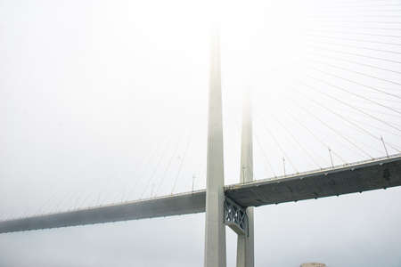 a beautiful bridge over the sea disappears in the fog. the bridge dissolves into the sky.の写真素材