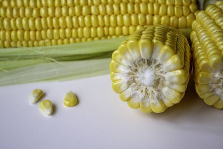 An ear of corn lies on a table. Ripe fresh corn with leaves. Piece of corn with three grain の写真素材