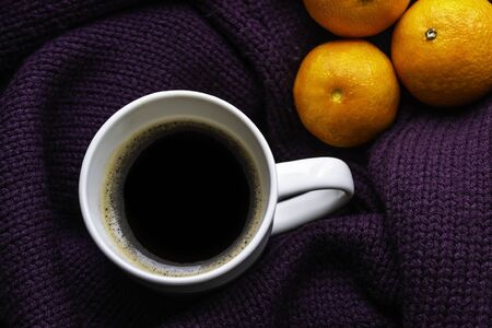 Tangerines and cup of coffee on a warm purple knitted sweater. Concept of winter moon and new year and christmas timeの写真素材