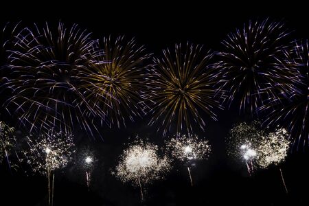 Veriety colorful fireworks on the night sky background. Many flashes of yellow with blue salute. holiday and fun conceptの写真素材