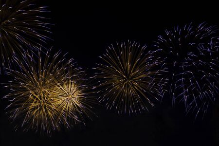 Veriety colorful fireworks on the night sky background. Many flashes of yellow with blue salute. holiday and fun conceptの写真素材