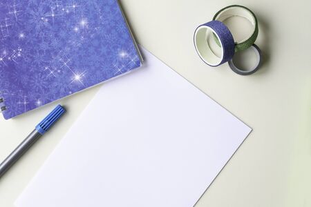 A white sheet of paper, a blue note with snowflakes, a felt-tip pen and a shiny multi-colored decorative scotch tape. The concept of concentration, winter and plans for the next year.の写真素材