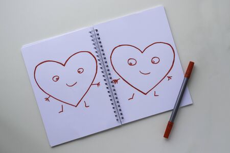 Hearts drawn by a red felt-tip pen on a white sheet in a notebook. Hearts with arms, legs and eyes. の写真素材