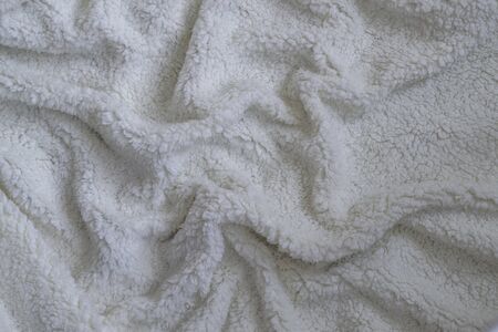 Texture of a soft plaid. Crumpled white warm blanket. Fabric crumpled in folds for background or wallpaper.の写真素材
