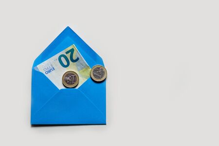 Banknote of 20 euros in blue envelope on a light background and two coins of one euro.の写真素材