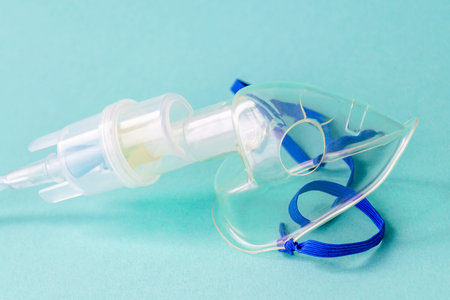 Transparent mask from an inhaler on a blue background. The device for inhalation of therapeutic...