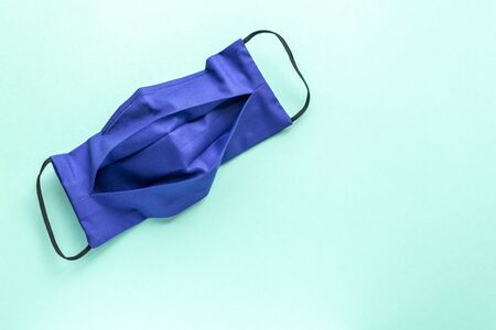 Medecine. Dark blue reusable mask on a mint plain background. Place for text.の写真素材