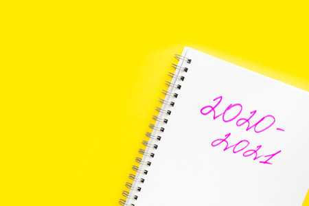 Back to school. The inscription 2020 - 2021 in a white notebook with a spiral, on a yellow...