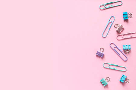 Back to school. Multi-colored paper clips laid out on a delicate pink background. Layout and flat lay with place for text.の写真素材