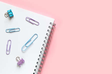 Layout and flat lay with place for text. Concept back to school. Multi-colored paper clips laid on a white notebook with a spiral.の写真素材