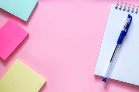 Three multi-colored stickers on a delicate pink background, a white notebook with a spiral and a blue pen to sirchu. Layout and flat lay with place for text. Concept back to school.の写真素材