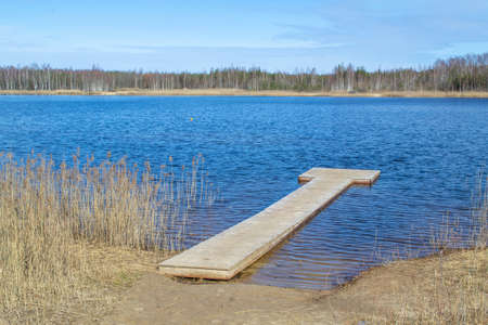 Lake shore, reeds and trail. Wooden pier on lake. Plains quarry in Olaine, Latviaの写真素材