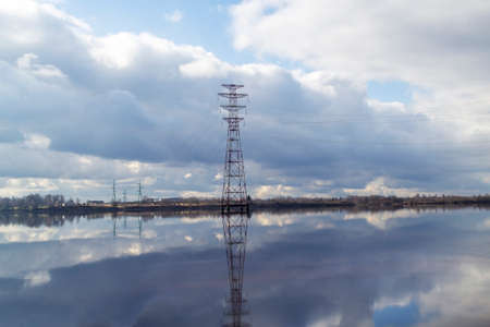 Electric transmission line across the Daugava river in Latvia. Scenic view. The nature of Latvia. Beautiful clouds in the blue sky and reflected in the water.の写真素材