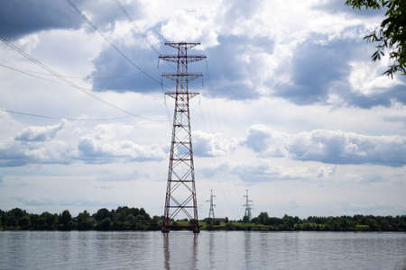 High voltage transmission power tower, electricity pylon stand on piles in water. Steel tower, used to support overhear power line. Nature landscape. Daugava river, Latviaの写真素材