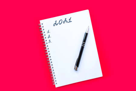 Notebook with a spiral and black pen on a red background. Planning list and numbers 1, 2 and 3. The inscription 2021. New Year and Christmas concept.の写真素材