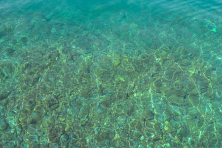 Texture of transparent shallow water surface. Rippling water background. Aerial view rocky bottom of Adriatic sea in sunny day. Journey Croatia.の写真素材
