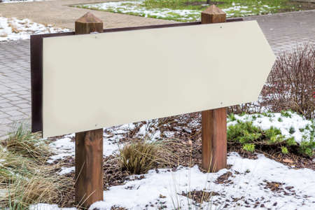 Wooden blank or empty signboard, grey signpost pole. Winter nature. Place for text, copy space.の写真素材