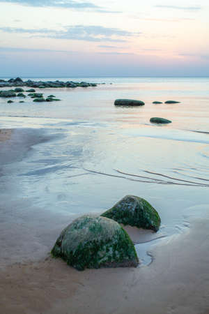 Stone coastline of Vidzeme in Latvia. Rocky beach of gulf of Riga on sunset. Beautiful sky and scenic view.の写真素材