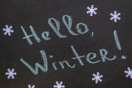 White snowflakes and handwritten inscription Hello Winter. Chalk inscription on black chalkboard.の写真素材