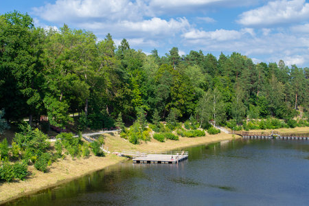 The embankment is overgrown with forest and a  bridge across the river.の写真素材