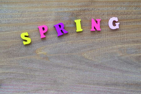 From small wooden, multi colored letters, maked inscription Spring. On a wooden, textured background. Copy space, place for text.の写真素材