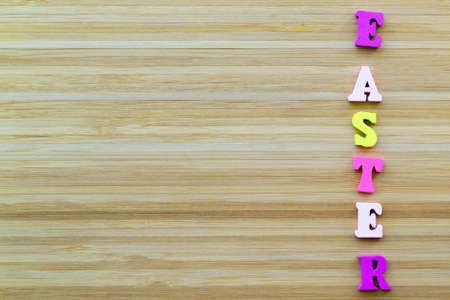 Letters lie on wooden background. Horiontal inscription Easter made from small wooden, multi colored letters.の写真素材
