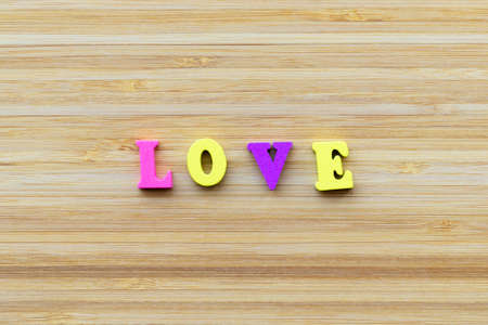 The inscription LOVE in colored wooden letters in a minimalist style. Striped, textured, wood background. The concept of love, relationships, Valentine's Day.の写真素材