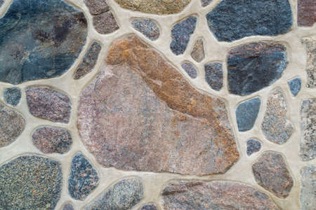 Close-up of wall. Stone and cement. Fragment of a colored, textured stonewall. Bright background. Copy space, place for textの写真素材