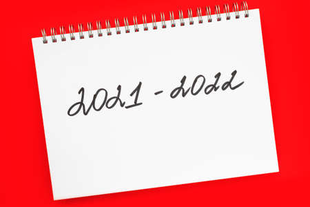 2021-2022 New school academic year. Handwriting inscription in white notepad, on vivid red background. Flat lay, top view. Back to school concept.の写真素材