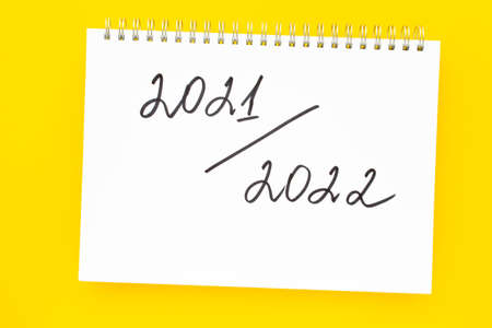 2021-2022 New academic year. Back to school concept. Handwriting inscription in white notepad, on vivid yellow background. Flat lay, top view.の写真素材
