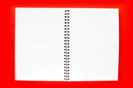 White notebook sheet with a spiral. Blank open notepad on red background top view. Concept of the Back to school, New year, Christmas. Layout, flat lay, copy space.の写真素材
