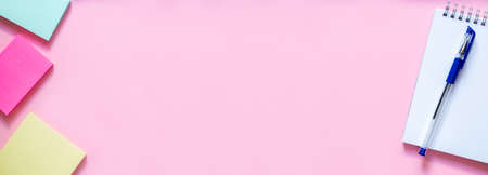 School office supplies. Stickers on a delicate pink background, white notebook with spiral and blue pen on top. Extra wide banner. Layout and flat lay with copy space. Concept back to school.の写真素材