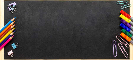 School office supplies. Various stationery: pencils, felt-tip pens, paper clips. School blackboard in wooden frame. Back to school and new academic year concept. Extra wide banner. Copy spaceの写真素材