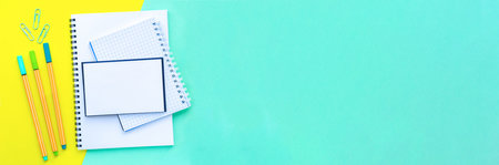 Banner. Stack of notebooks on a spiral overlap. Bright, colorful yellow with mint color background. Back to school concept. Copy space, top view, flat lay.の写真素材