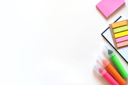 Markers, stickers and notepad on a light white background. Colored office school supplies on the...