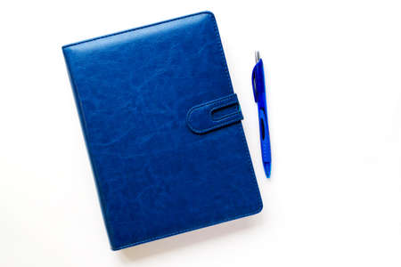 Dark blue notebook in a leather case on a light background. The handle is next to it. Planning and self-development conceptの写真素材