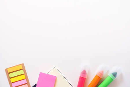Colored office school supplies from the underside. Markers, stickers and notepad on a light white background. Flatlay with copy space.の写真素材