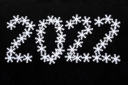 Inscription 2022 made of beautiful white snowflakes. On a dark, black chalkboard background. New Year and Christmas mood conceptの写真素材