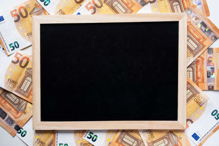 Black clarkboard and background of 50 euro banknotes. Flat lay. Copy space, top view.の写真素材