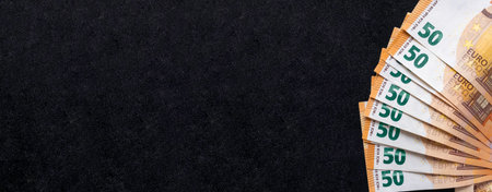 Banner with fan of banknotes on black clarkboard. 50 Euro money flat lay. Copy space, top view.の写真素材