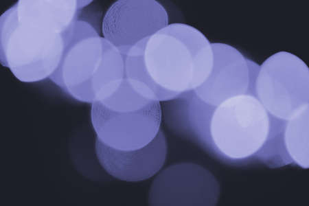 Circle bokeh in very peri color of the 2022 year. Purple defocused light. Christmas twinkling lights background bokeh. New year mood.の写真素材