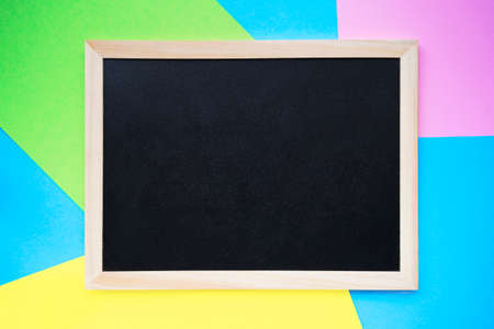Empty chalkboard on line of pink, yellow, green and light blue paper background. Back to school or schools out concept. Copy space, top viewの写真素材