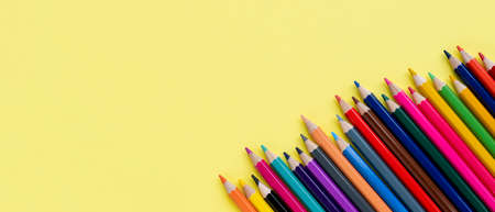 Banner with colored wooden pencils row on yellow background close-up. Set of color pencils with copy space. top view.の写真素材