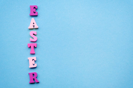 Vertical inscription Easter from wooden colored letters on a light blue background. Flat lay, copy spaceの写真素材