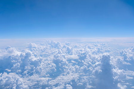 Blue sky and many white cumulus clouds. Aerial view from airplane window. Background with copy space.の写真素材